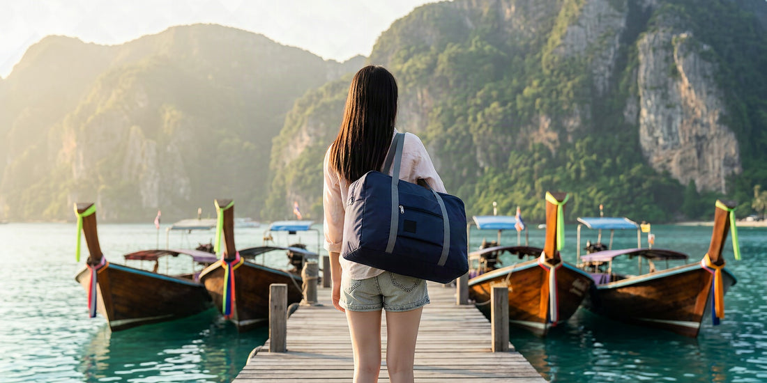 Voyageur avec un sac de voyage pliable sur un ponton de la mer d'Andaman en janvier, longtails et falaises karstiques