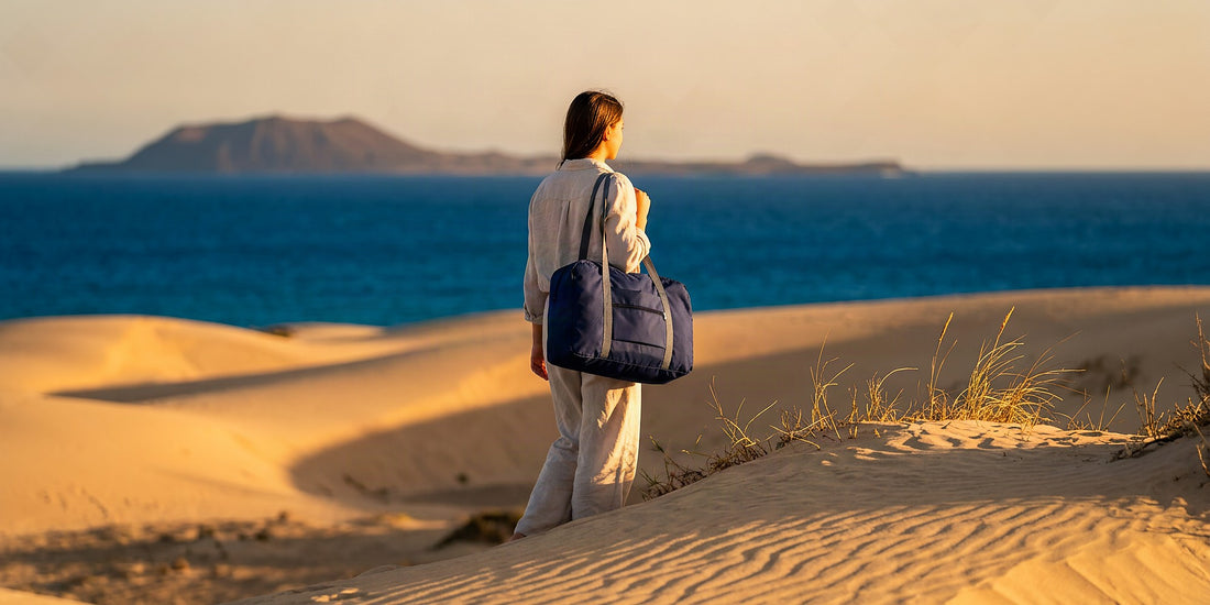 Voyageur avec un sac de voyage pliable sur les dunes de Corralejo à Fuerteventura en février